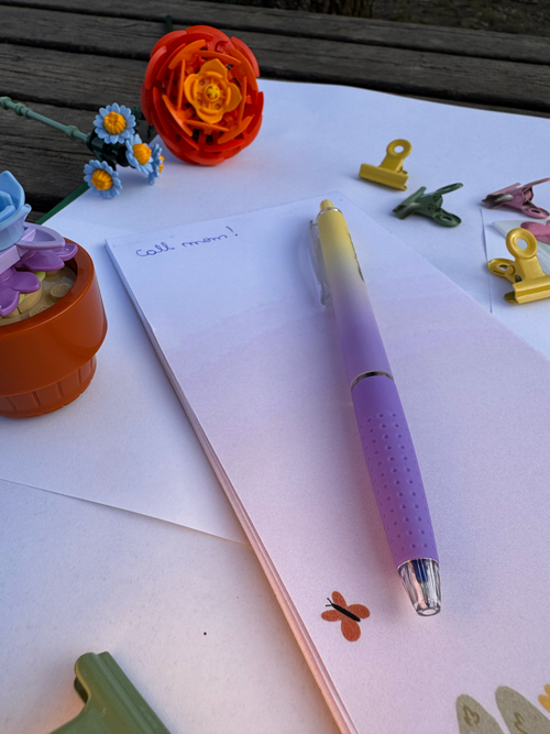 Purple pen on a piece of paper with decorative items around