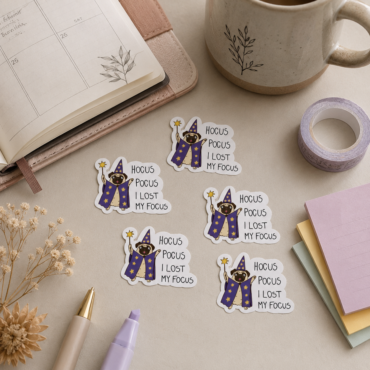 Five die-cut stickers featuring a cartoon wizard with a purple robe and gold hat, accompanied by the text 'HOCUS POCUS I LOST MY FOCUS', arranged on a beige desk with stationery props including a notebook, mug, washi tape, and sticky notes.