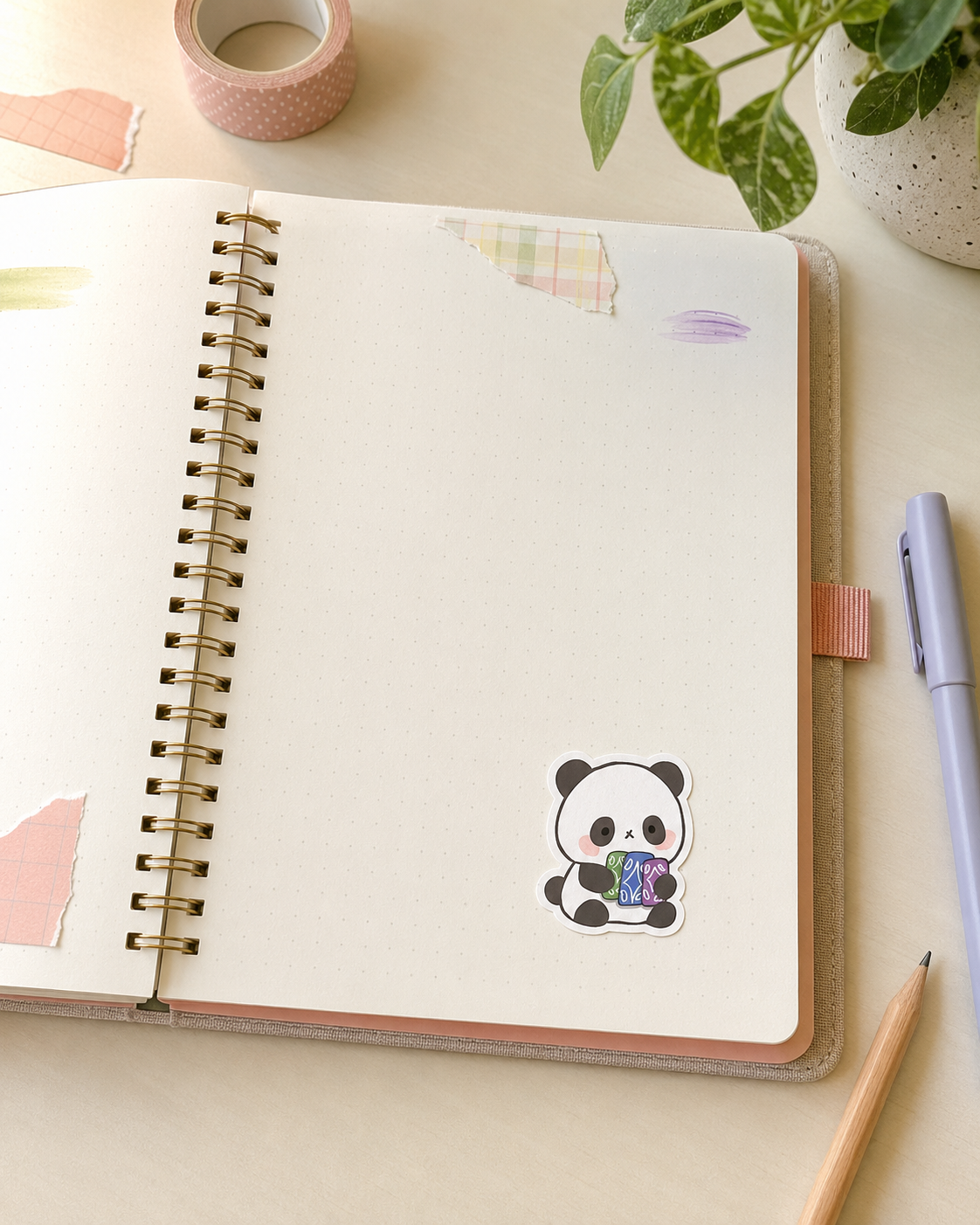 A spiral-bound notebook lies open on a light beige desk, featuring a cute cartoon panda sticker holding a colorful basket on the page. The scene is styled with a lavender pen, a pencil, washi tape, and a potted plant.